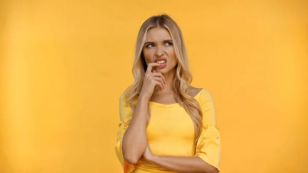 Gestresste Frau in Bluse hält Finger in Lippennähe isoliert auf gelb — Stockfoto