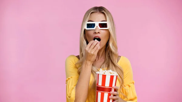 Schockierte Frau in 3D-Gläsern isst Popcorn isoliert auf rosa — Stockfoto