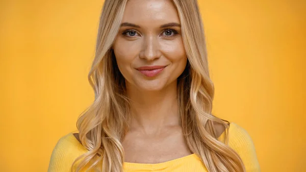 Donna bionda in camicetta sorridente alla macchina fotografica isolata sul giallo — Foto stock