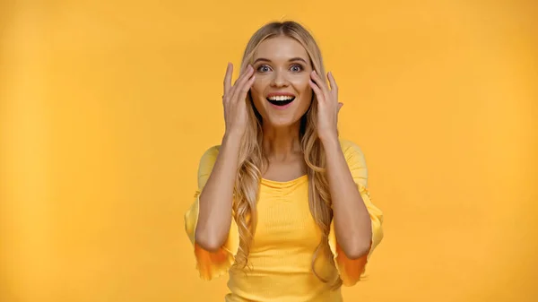 Amazed blonde woman touching face isolated on yellow — Stock Photo