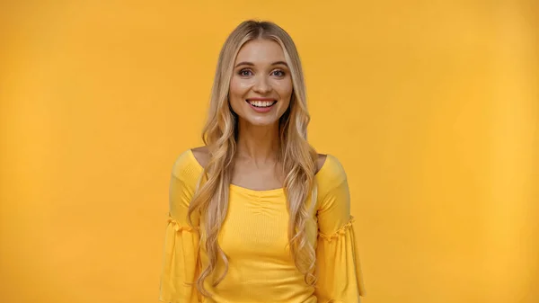 Smiling blonde woman looking at camera isolated on yellow — Stock Photo