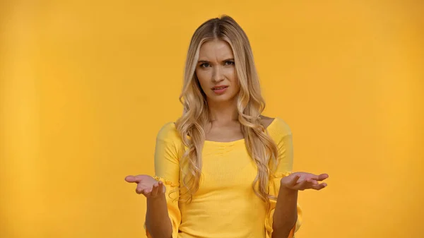 Confused blonde woman in blouse pointing with hands isolated on yellow — Stock Photo