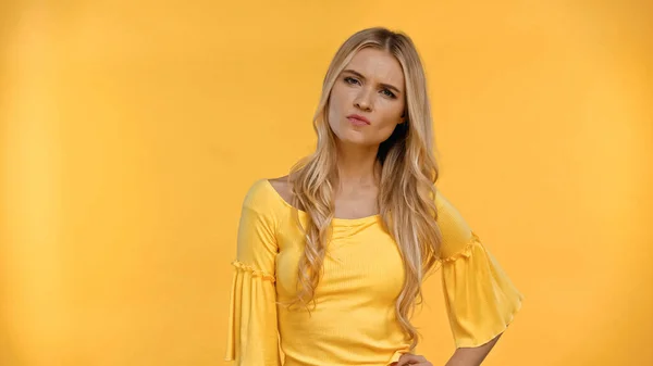 Сердита блондинка в блузці дивиться на камеру ізольовано на жовтому — стокове фото