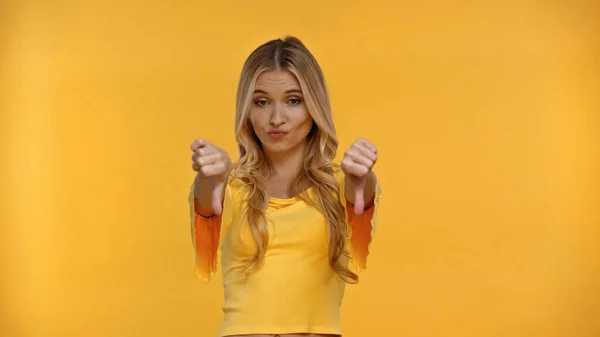 Offended blonde woman showing thumbs up isolated on yellow — Stock Photo