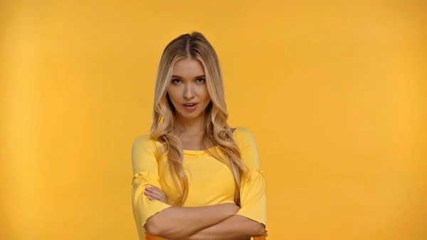 Скептична блондинка в блузці дивиться на камеру ізольовано на жовтому — стокове фото