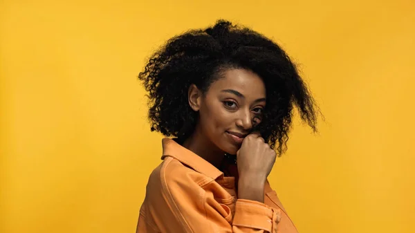 Jeune et joyeuse femme afro-américaine aux cheveux bouclés isolé sur jaune — Photo de stock