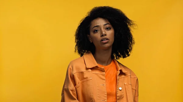 Mujer afroamericana rizada con frenos mirando a la cámara aislada en amarillo - foto de stock