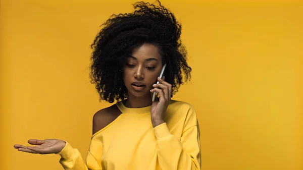 Lockige afrikanisch-amerikanische Frau telefoniert isoliert auf gelb — Stockfoto