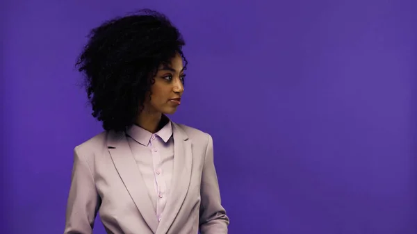 Jovem mulher de negócios afro-americana em blazer olhando para longe isolado em roxo — Fotografia de Stock