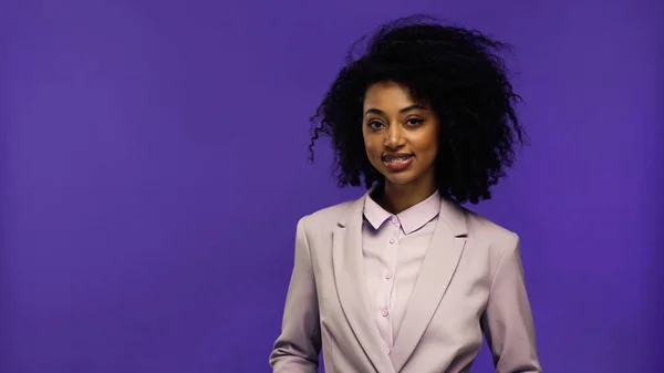 Cheerful african american businesswoman with braces looking at camera isolated on purple — Stock Photo