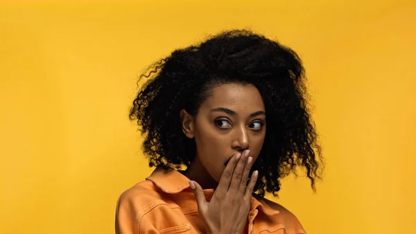 Шокированная африканская американская молодая женщина смотрит в сторону изолированной на желтый — стоковое фото