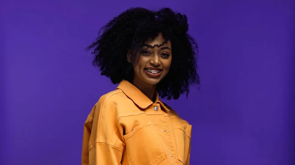 Positive femme afro-américaine avec bretelles souriant isolé sur violet — Photo de stock
