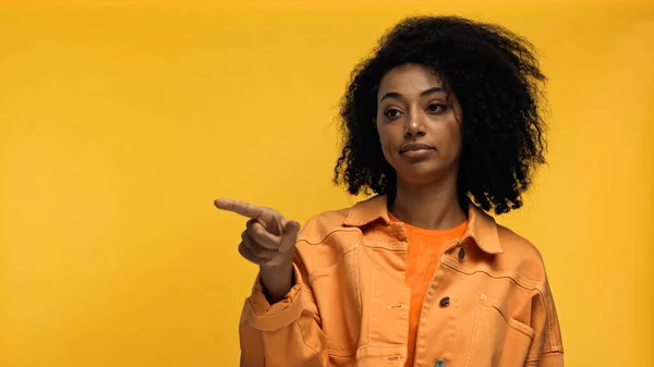 Skeptical african american woman pointing with finger isolated on yellow — Stock Photo