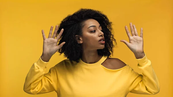 Pretty young african american woman showing hands palms while performing mime acting isolated on yellow — Stock Photo