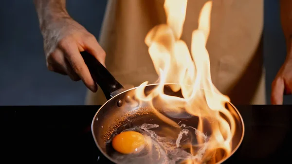 Vista ritagliata dell'uomo frittura uovo di pollo con il metodo flambe — Foto stock