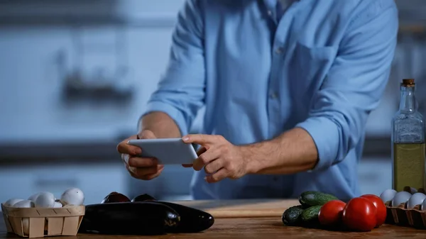 Cropped view of man taking photo of fresh ingredients on table — Stock Photo