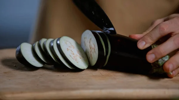 Close up view of man cutting eggplant on chopping board — Stock Photo