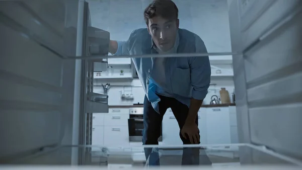 Curious man looking into empty fridge in kitchen — Stock Photo