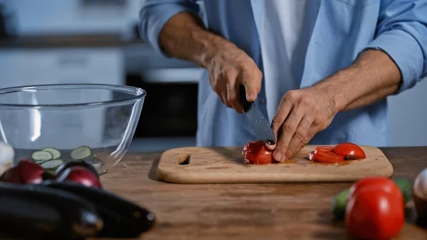 Vista cortada do homem cortando tomates maduros perto de berinjelas desfocadas — Fotografia de Stock