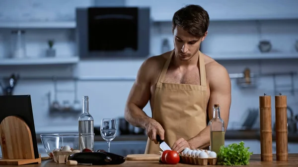 Shirtless man in apron cooking in modern kitchen — Stock Photo