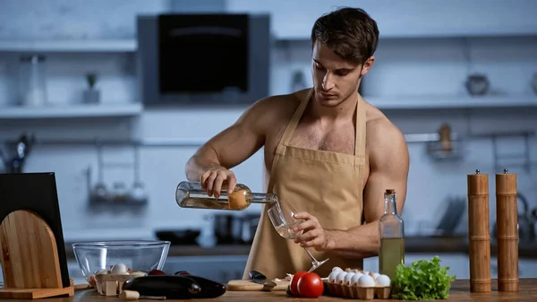 Homem sem camisa em avental derramando vinho branco em vidro — Fotografia de Stock