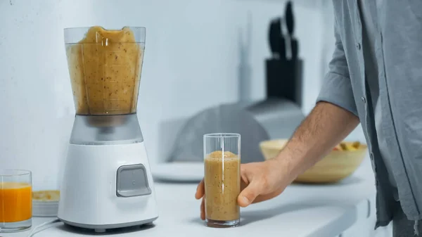 Vue partielle de l'homme près du verre de smoothie frais et mélangeur électrique — Photo de stock