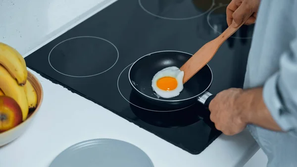 Visão parcial do homem fritando ovo enquanto prepara o café da manhã — Fotografia de Stock