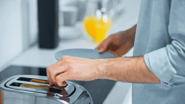 Cropped view of man preparing toasts in electric toaster in kitchen — Stock Photo
