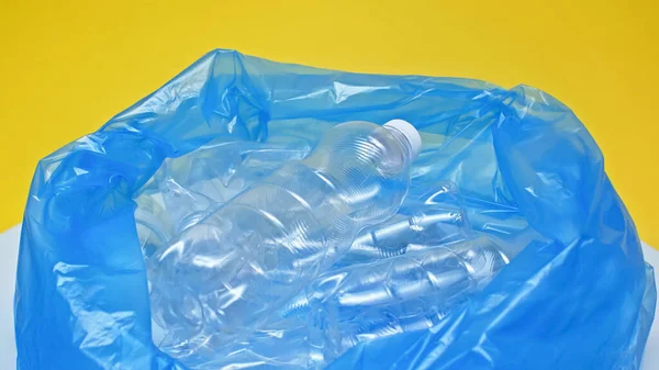 Botellas de plástico en bolsa de basura aislado en amarillo - foto de stock