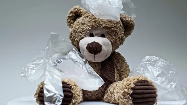 Plastic bags falling on teddy bear isolated on grey — Stock Photo