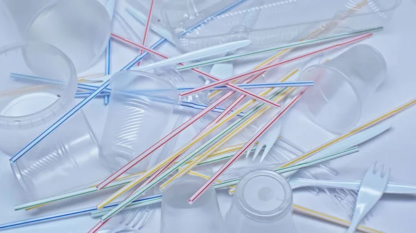 Vista de alto ângulo de copos de plástico perto de garfos e palhas em branco, conceito ambiental — Fotografia de Stock
