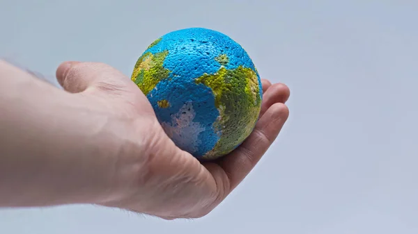 Partial view of man holding small globe in hand isolated on grey — Stock Photo