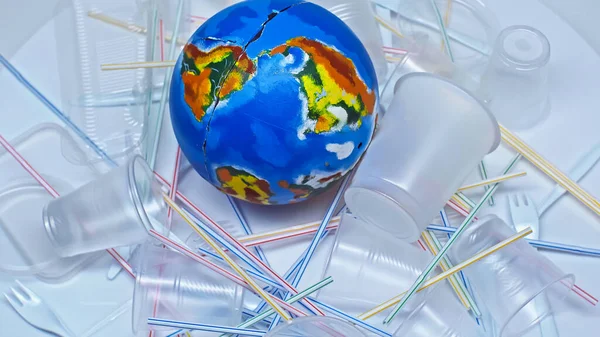 Globe près des gobelets en plastique et des déchets sur blanc — Photo de stock