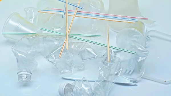 Vasos de plástico cerca de tenedores y pajitas de colores en blanco - foto de stock