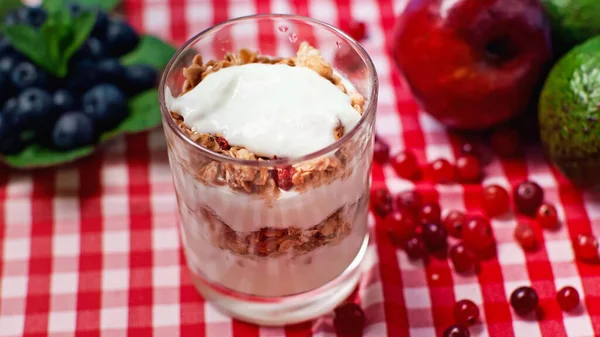 Fresh yogurt with granola in glass on plaid tablecloth — Stock Photo