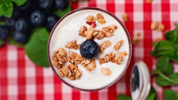 Top view of blueberry and granola on top of fresh yogurt in glass — Stock Photo