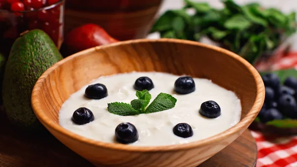 Nahaufnahme von frischer Pfefferminze und Blaubeeren in Holzschale mit Joghurt — Stockfoto