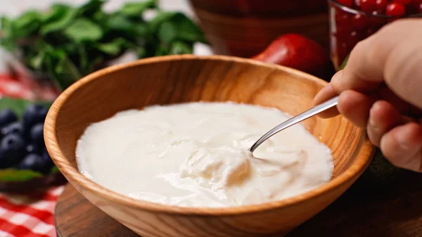 Cropped view of man holding spoon near tasty yogurt in bowl — Stock Photo