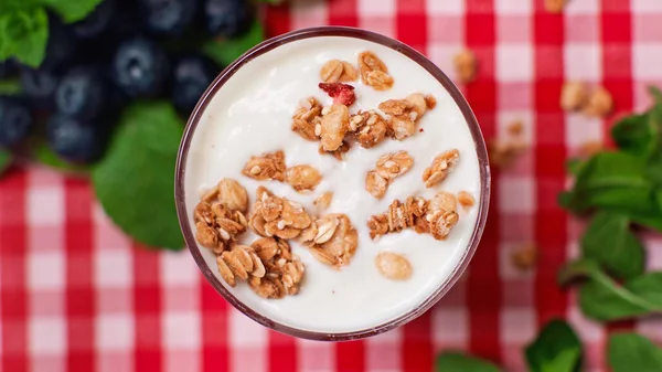 Top view of crunchy granola on top of fresh yogurt in glass — Stock Photo