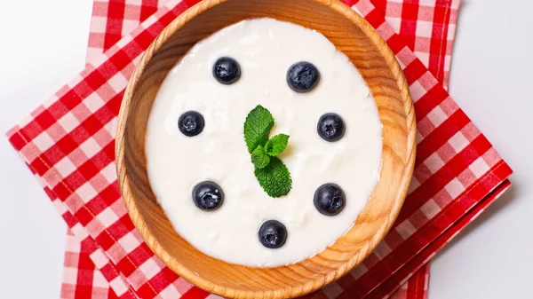 Vista superior de los arándanos y la menta en un tazón con sabroso yogur aislado en blanco - foto de stock