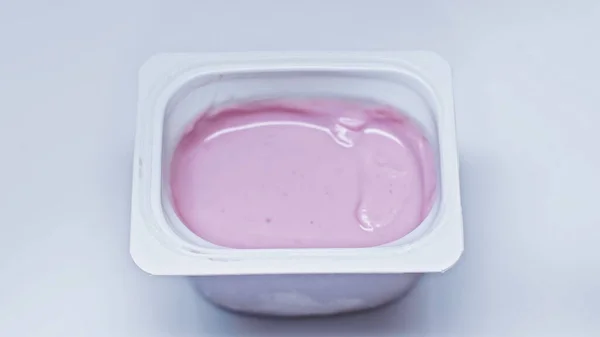 Top view of plastic container with pink yogurt on white — Stock Photo