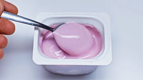 Cropped view of man holding spoon near container with yogurt on white — Stock Photo