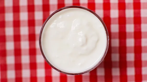 Top view of bowl with fresh yogurt on checkered background — Stock Photo