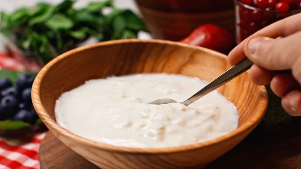 Partial view of man holding spoon near yogurt in bowl — Stock Photo