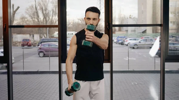 Sportsman holding dumbbells while training in gym — Stock Photo