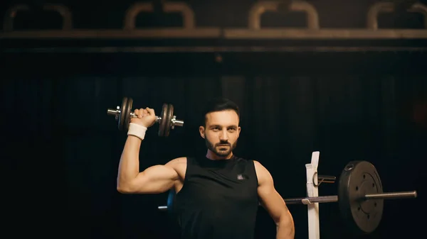 Morena deportista de entrenamiento con mancuerna sobre fondo oscuro - foto de stock