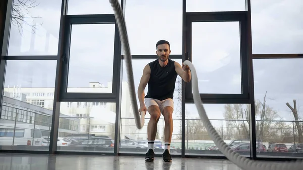 Entrenamiento de deportista atlético con cuerda de batalla borrosa en el gimnasio - foto de stock