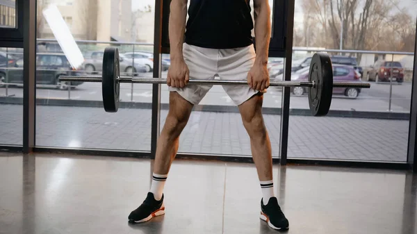 Cropped view of athletic sportsman holding barbell in sports center — Stock Photo