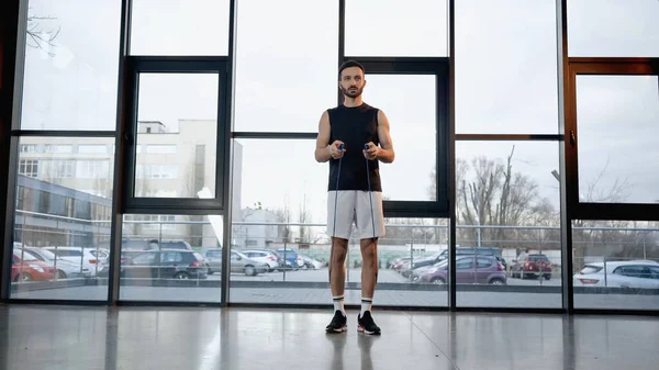 Brunette sportsman holding jump rope in gym — Stock Photo
