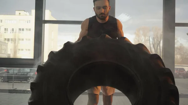 Sportsman lifting tire while training in gym — Stock Photo